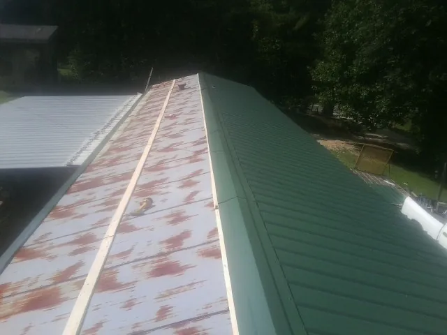 Old rusted panels beside newly installed green metal roofing — Wind Damage Roof Repair by Roofing Brothers in Boulder Creek