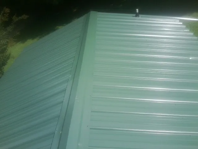 New green metal panels meeting at the ridge of a roof — Flat Roof Repair work by our crew in Boulder Creek