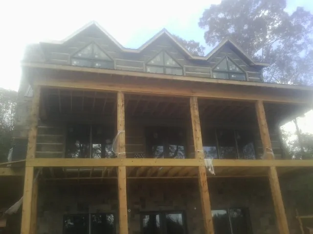 Dormers and porch framing on a large log home under construction — Roof Coating work by our crew in Boulder Creek