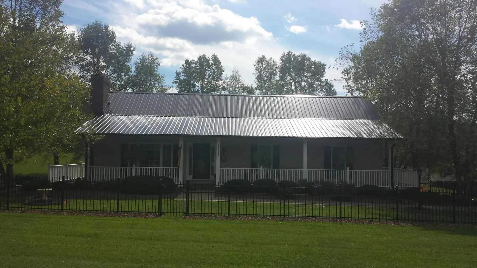 Gray metal roof on a brick ranch with a full width front porch — Gutter Guard Installation work by our crew in Boulder Creek