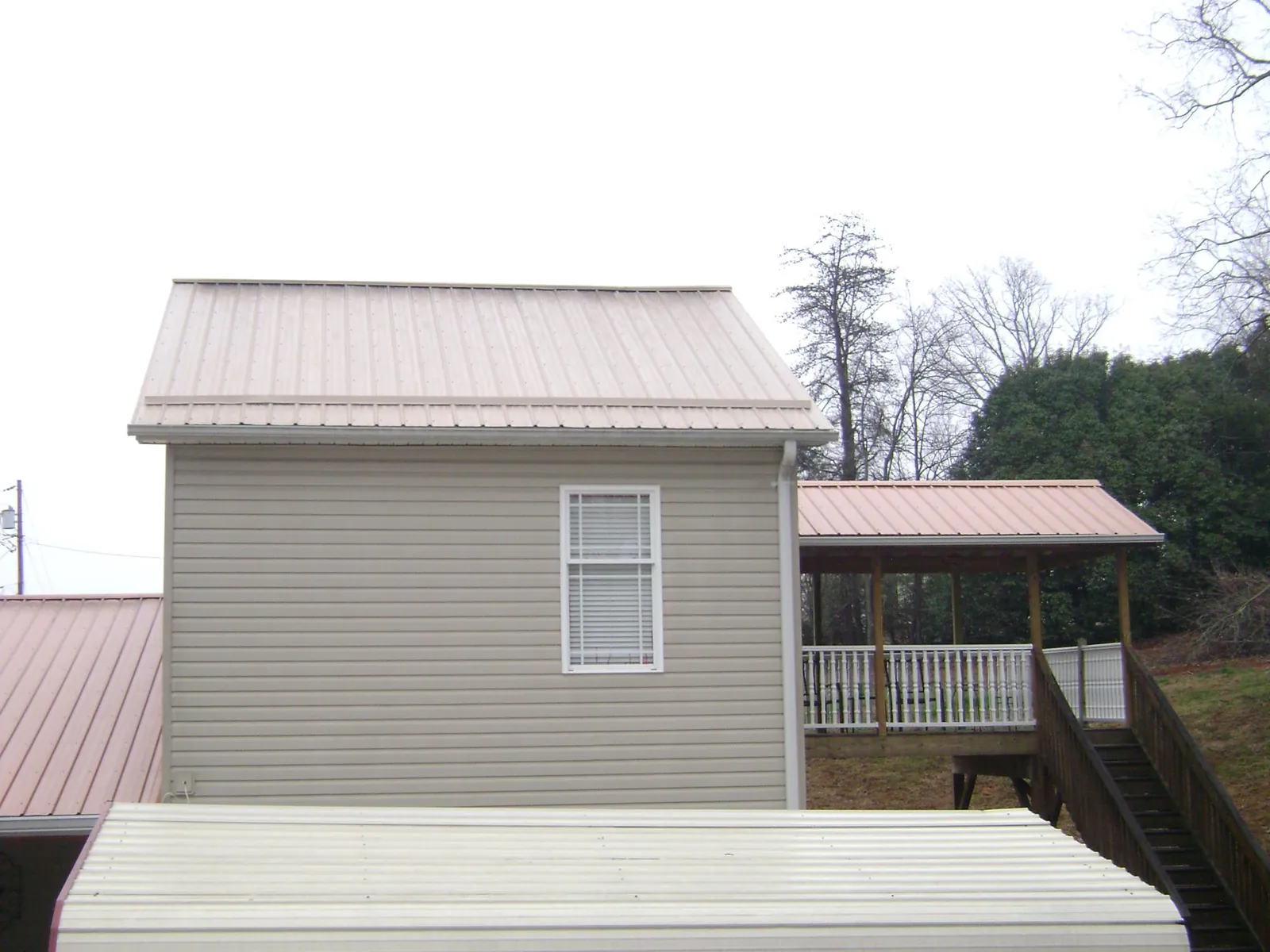 Tan metal roofs on a two story addition and attached porch, from a Roof Replacement job in Boulder Creek
