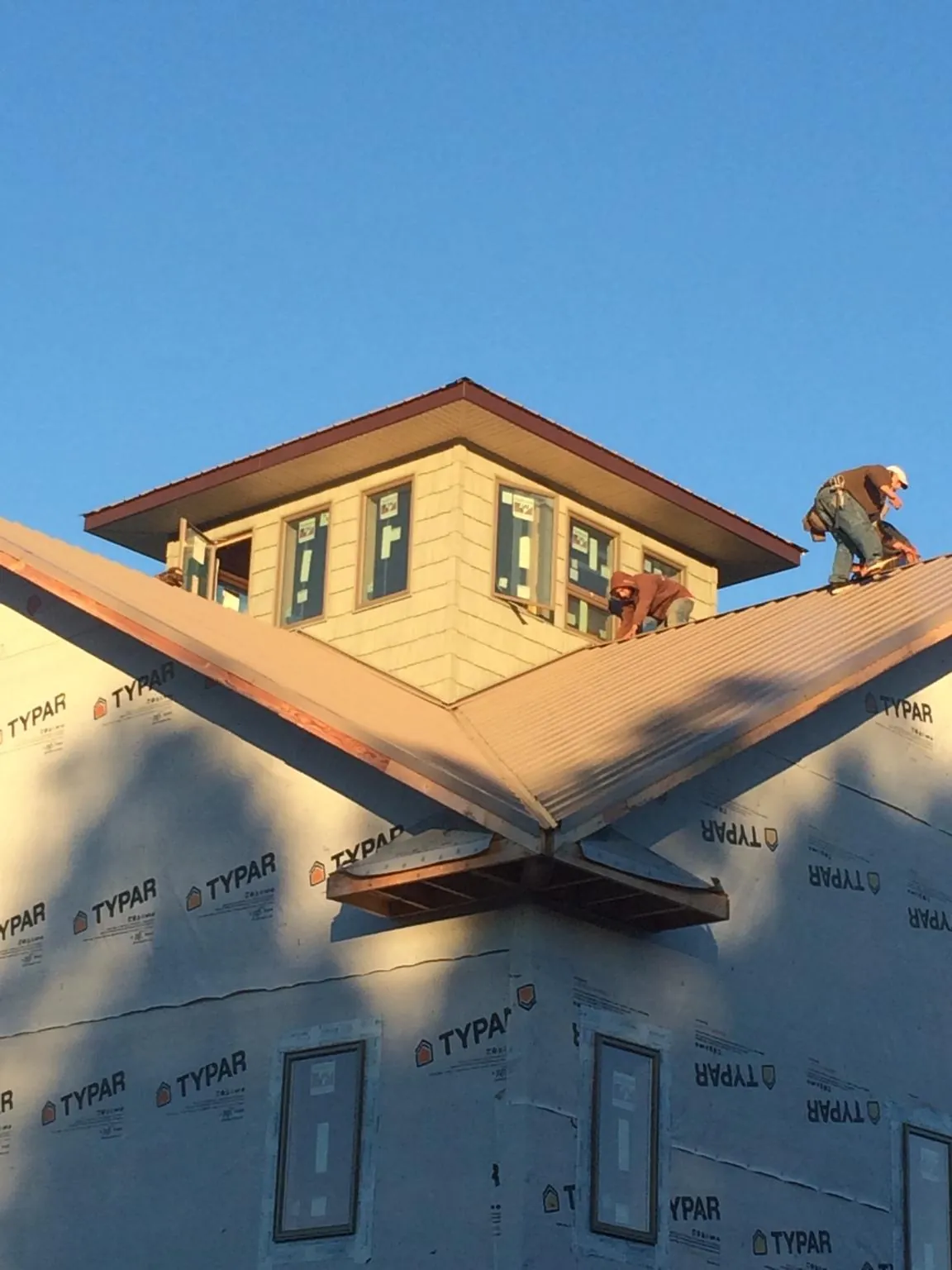 Roofers working around a rooftop cupola on a new metal roof at sunset — Roof Waterproofing in Boulder Creek by Roofing Brothers